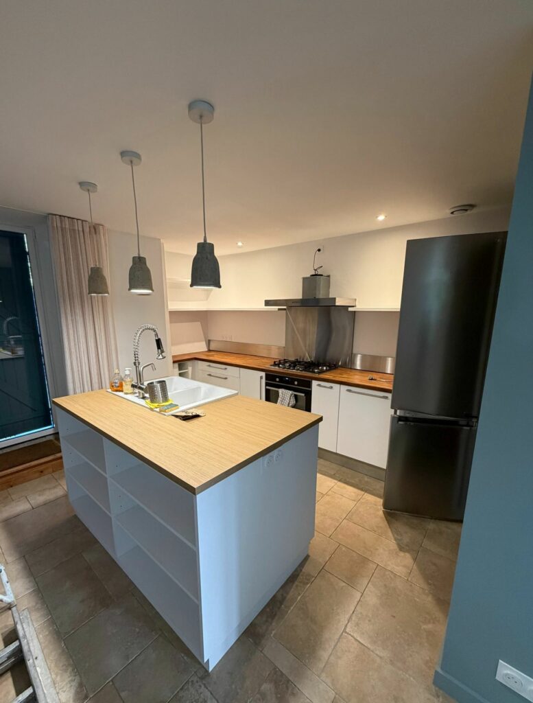 Cuisine rénovée avec îlot central et plan de travail en bois